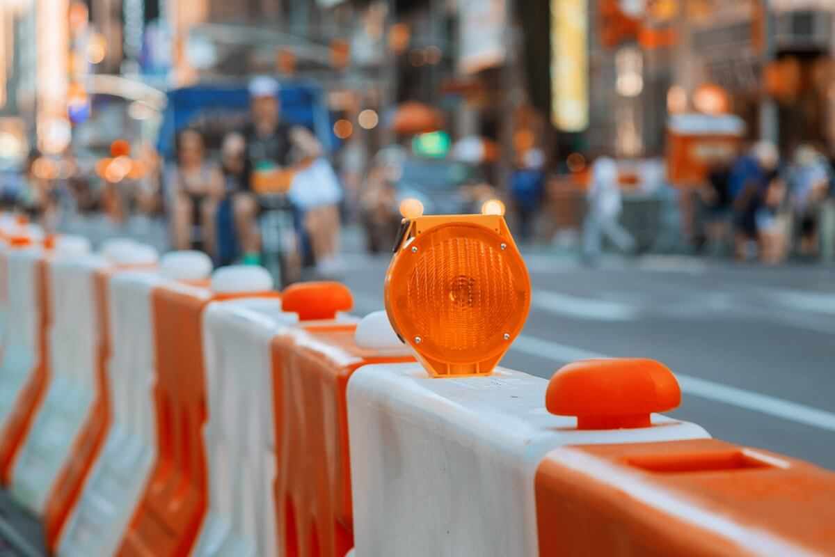 Orange construction barricade with warning light on a city street.
